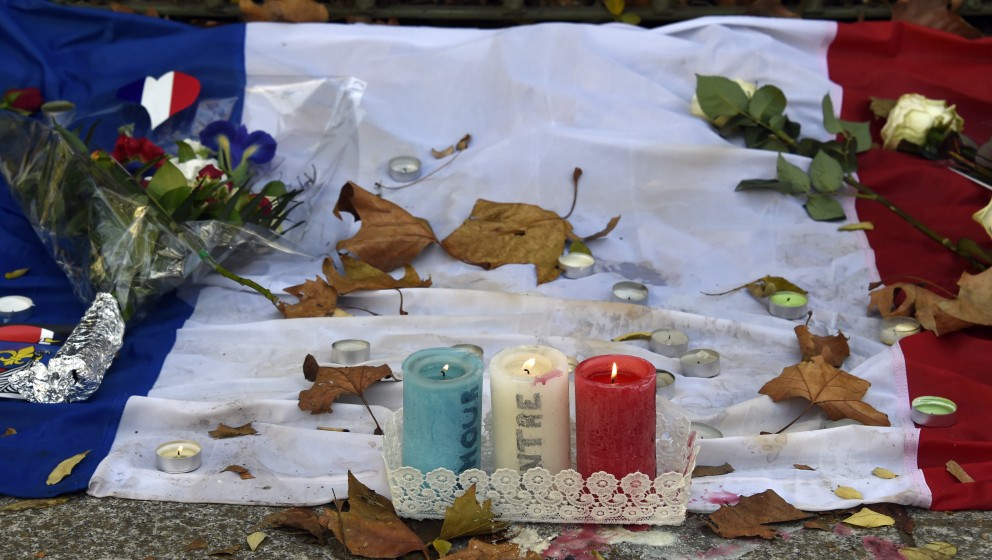 Candles bearing the colours of the French flag burn at a makeshift memorial for the victims of the attacks, on November 18, 2