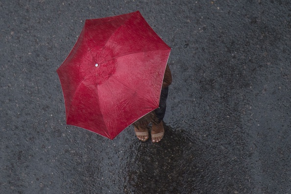 TOPSHOT - A woman shelters under an umbrella under heavy rain and strong wind in Rio de Janeiro, Brazil, on February 29, 2016
