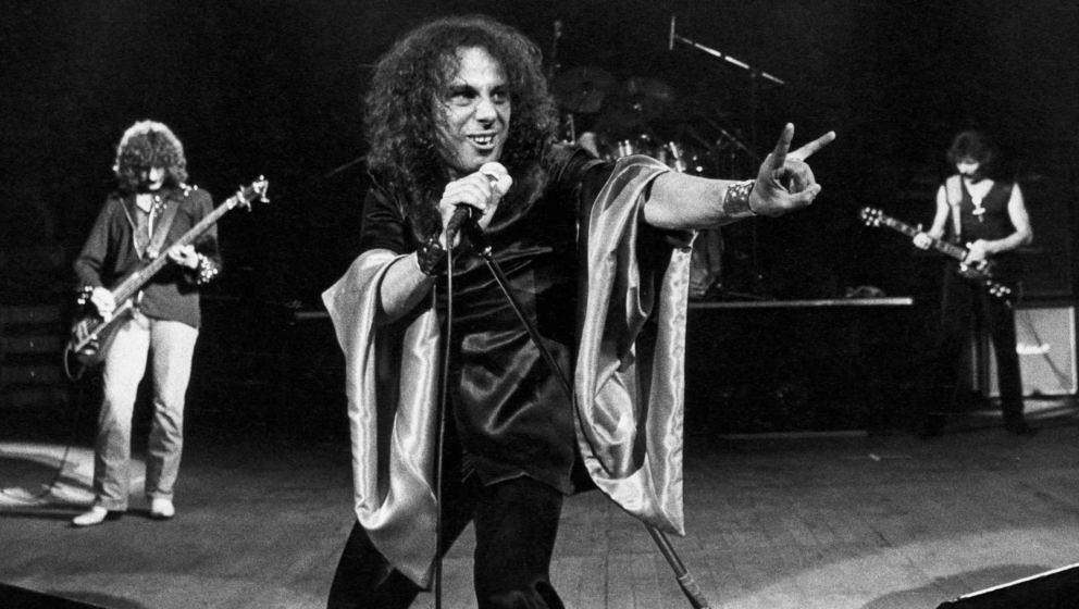 Ronnie James Dio macht zwischen Geezer Butler (l.) und Tony Iommi seine berühmten Teufelshörner