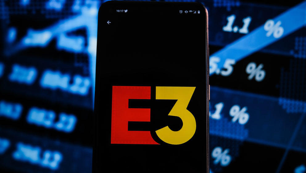 POLAND - 2021/06/15: In this photo illustration an E3 logo displayed on a smartphone with stock market percentages on the bac
