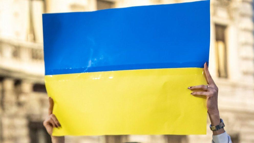 Eine Mailänder Demonstrantin hält die Flagge der Ukraine in die Luft
