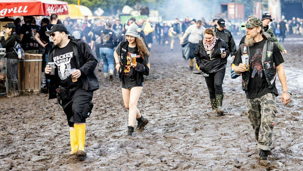 Visitors of the Wacken Open Air are fighting against the mud on the festival ground on August 1, 2023. Wacken Open Air, one o