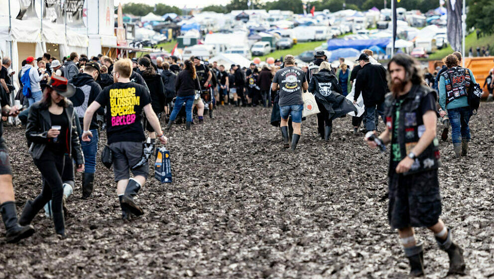 Visitors of the Wacken Open Air are fighting against the mud on the festival ground on August 1, 2023. Wacken Open Air, one o